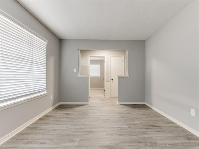 spare room with light wood-style floors and baseboards