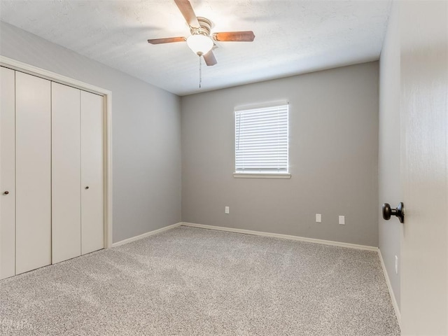 unfurnished bedroom featuring light carpet, a closet, a ceiling fan, and baseboards