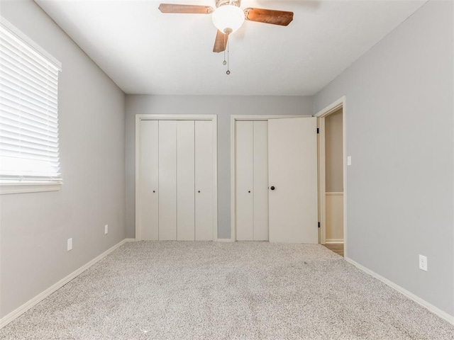 unfurnished bedroom featuring ceiling fan, carpet flooring, two closets, and baseboards