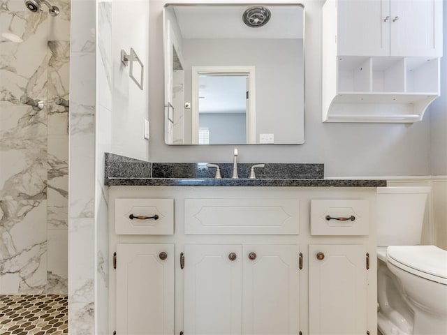 full bath featuring toilet, a marble finish shower, and vanity