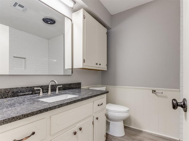 bathroom featuring visible vents, toilet, wainscoting, vanity, and wood finished floors