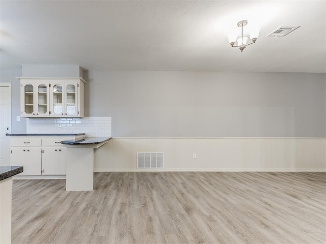 kitchen featuring visible vents, dark countertops, light wood-style flooring, glass insert cabinets, and white cabinetry