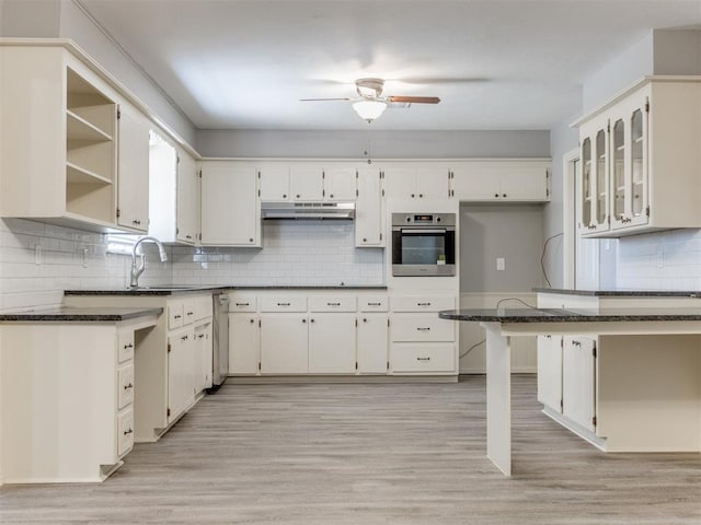 kitchen with under cabinet range hood, stainless steel appliances, white cabinetry, dark stone counters, and open shelves