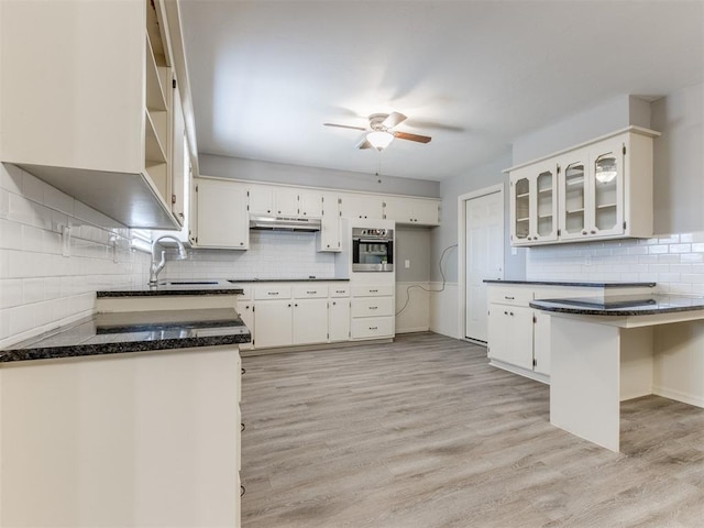 kitchen with glass insert cabinets, oven, white cabinets, and a sink