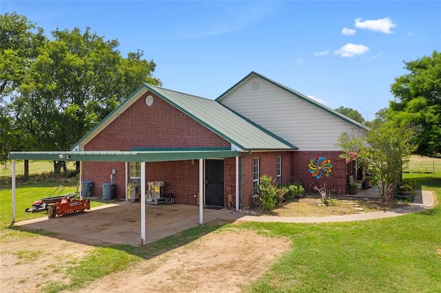 view of front of house with metal roof, an attached carport, brick siding, driveway, and a front lawn