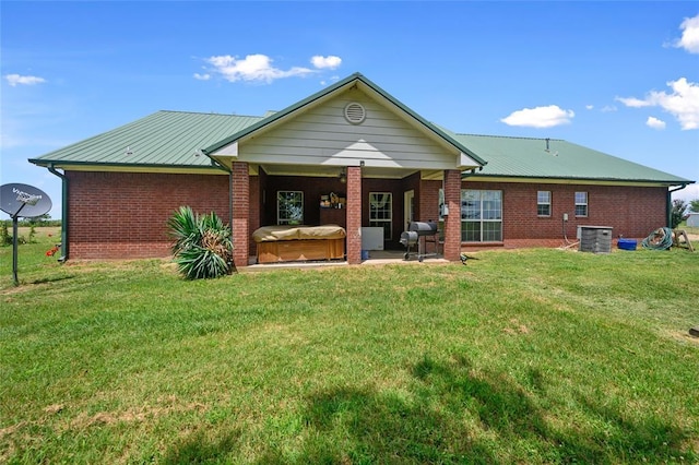 back of property featuring brick siding, a lawn, a patio area, and cooling unit