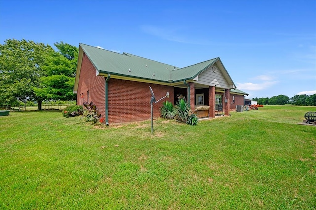 back of house featuring metal roof, a lawn, and brick siding