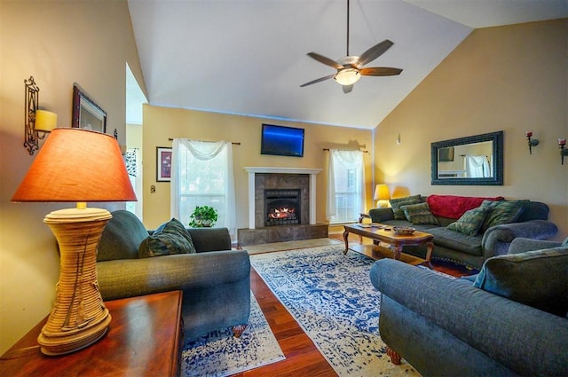 living room with high vaulted ceiling, a tile fireplace, a ceiling fan, and wood finished floors