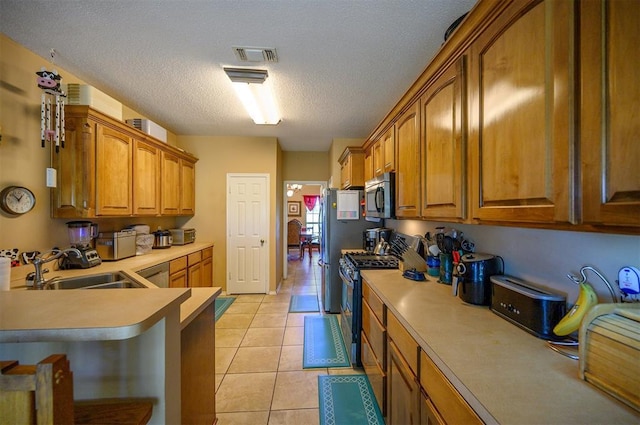 kitchen with a sink, brown cabinetry, stainless steel appliances, and light countertops