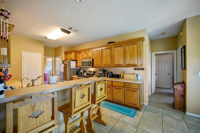 kitchen with light tile patterned floors, light countertops, visible vents, appliances with stainless steel finishes, and a textured ceiling