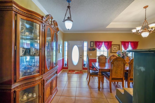 dining area with a textured ceiling, ornamental molding, light tile patterned flooring, and an inviting chandelier