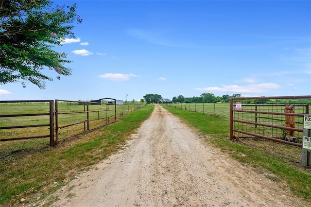 view of street featuring dirt driveway and a rural view