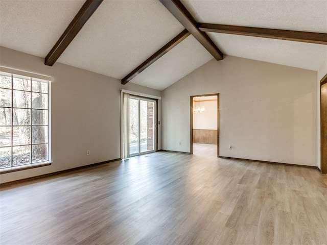 unfurnished living room featuring vaulted ceiling with beams, light wood-type flooring, and plenty of natural light