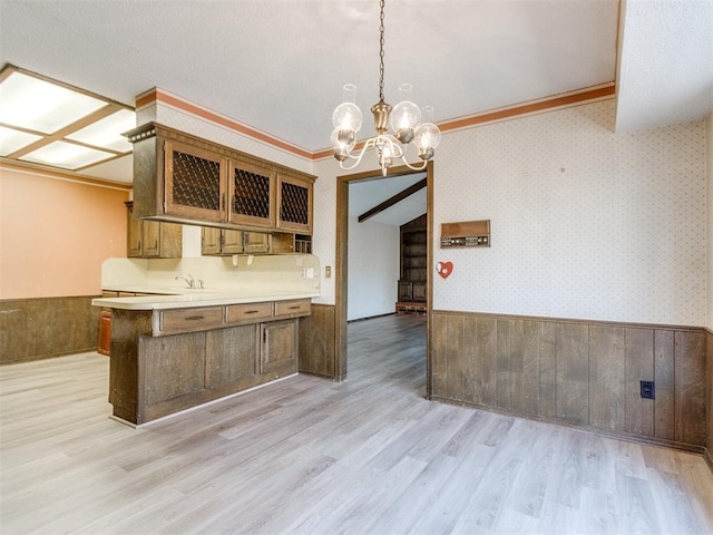 kitchen with wallpapered walls, glass insert cabinets, and wainscoting