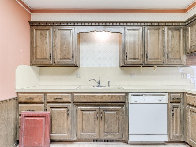 kitchen with a wainscoted wall, crown molding, light countertops, white dishwasher, and a sink