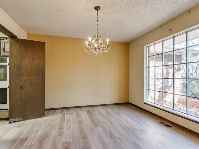 unfurnished dining area with light wood finished floors, visible vents, and a healthy amount of sunlight