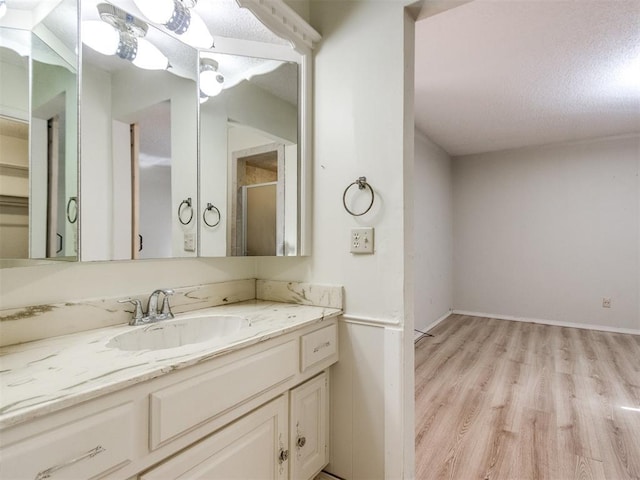 full bathroom with a shower with shower door, wood finished floors, vanity, and baseboards