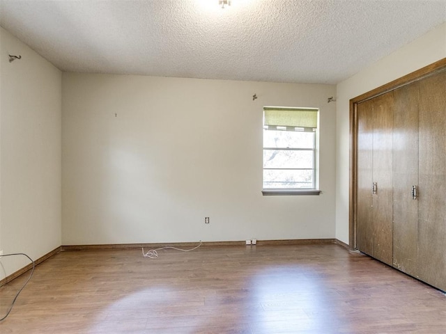 unfurnished bedroom with a closet, a textured ceiling, and wood finished floors