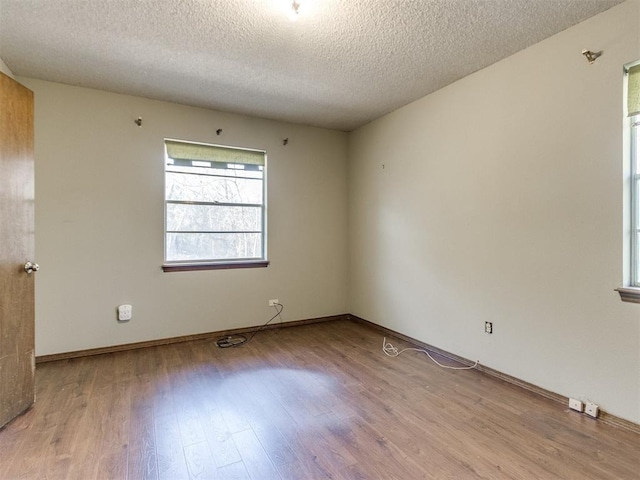 empty room featuring a textured ceiling, baseboards, and wood finished floors