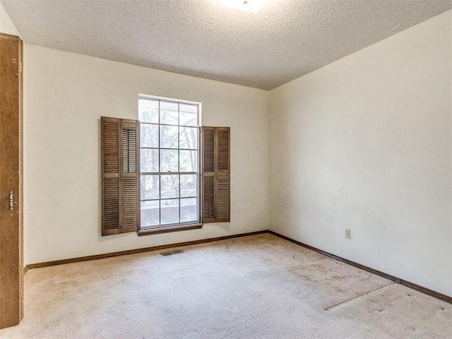 empty room featuring baseboards, carpet, visible vents, and a textured ceiling