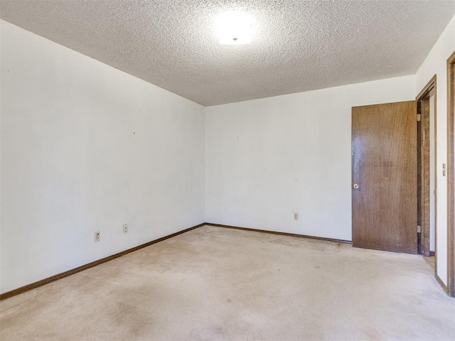 empty room featuring carpet, baseboards, and a textured ceiling