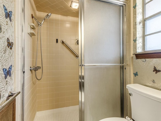 full bathroom featuring a stall shower, toilet, and wallpapered walls