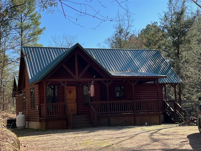 view of front of house with covered porch, metal roof, and faux log siding