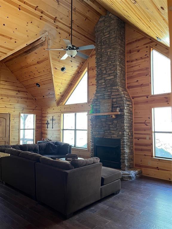 living room with dark wood-type flooring, wood walls, wooden ceiling, and a healthy amount of sunlight