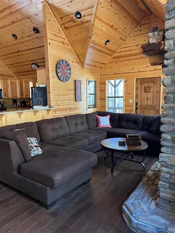 living room with high vaulted ceiling, dark wood-style flooring, wood ceiling, and wooden walls