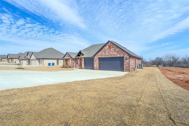 view of front facade with a garage, driveway, brick siding, and cooling unit