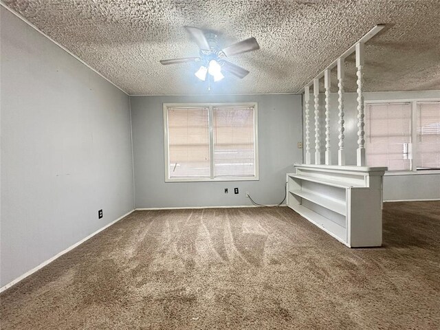 carpeted empty room with ceiling fan, a textured ceiling, and baseboards