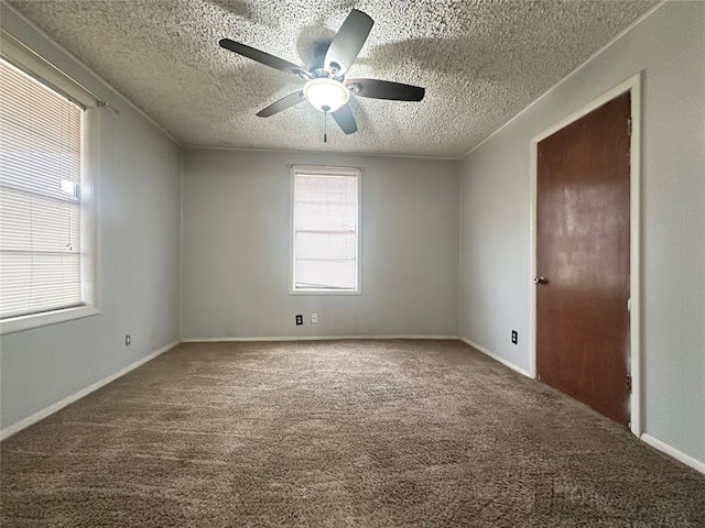 spare room featuring a textured ceiling, carpet flooring, a ceiling fan, and baseboards