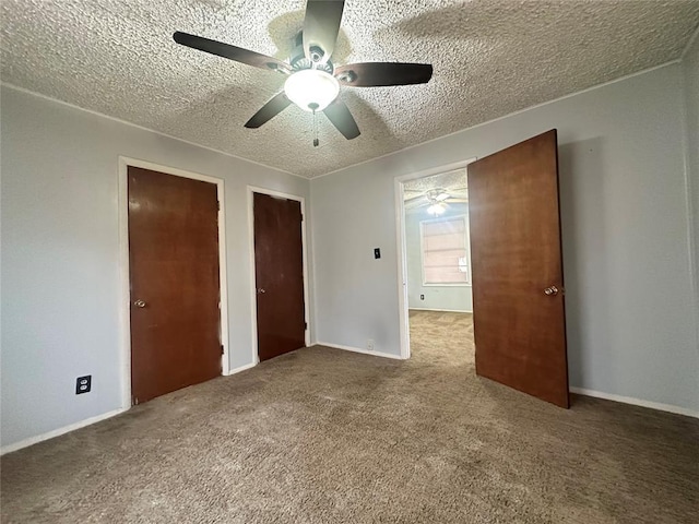 unfurnished bedroom featuring baseboards, ceiling fan, a textured ceiling, carpet flooring, and multiple closets