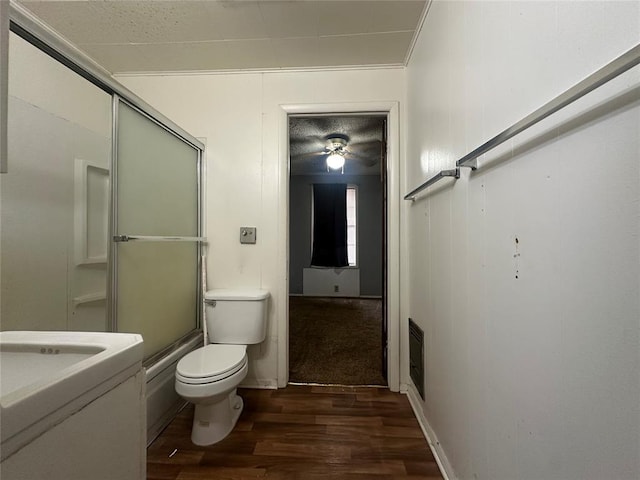 bathroom featuring ornamental molding, wood finished floors, an enclosed shower, and toilet