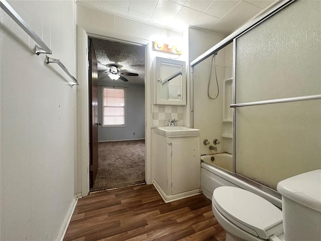 bathroom featuring ceiling fan, toilet, bath / shower combo with glass door, wood finished floors, and vanity