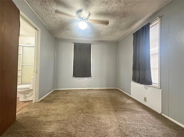 unfurnished room featuring carpet flooring, ceiling fan, a textured ceiling, and baseboards