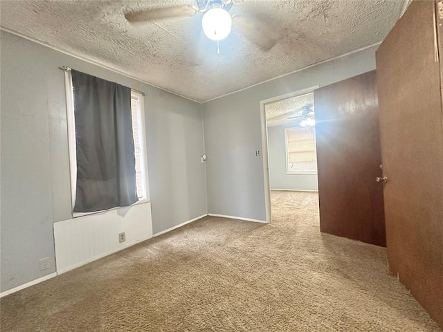 carpeted empty room with ceiling fan and a textured ceiling