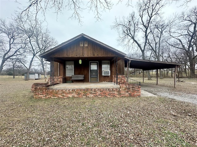 view of front of home with covered porch, driveway, an attached carport, and cooling unit