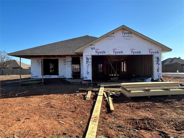 unfinished property with a garage and a shingled roof