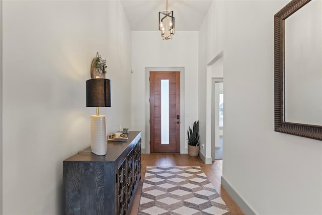 foyer entrance with light wood-style floors, a chandelier, and baseboards