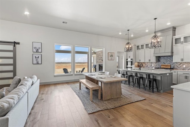 dining area featuring light wood finished floors, a barn door, visible vents, baseboards, and recessed lighting