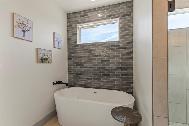 full bathroom featuring a freestanding bath and baseboards