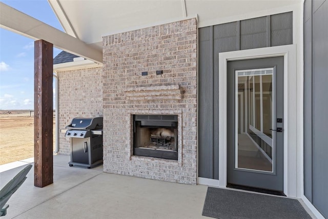 view of patio with an outdoor brick fireplace and area for grilling