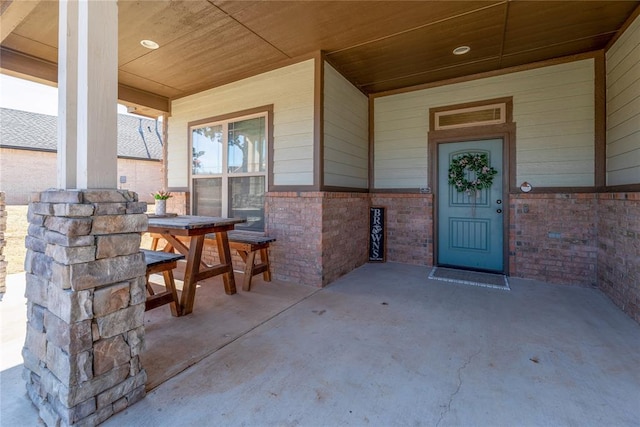 entrance to property featuring outdoor dining area, covered porch, and brick siding