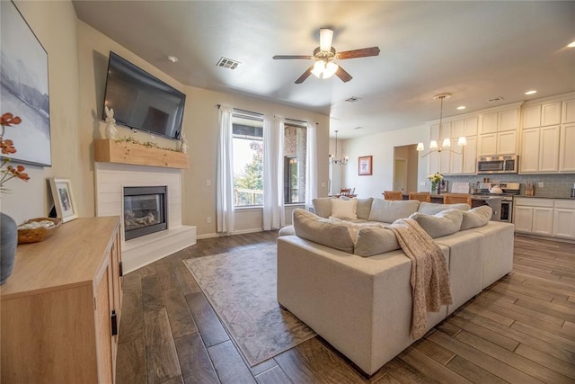 living area featuring recessed lighting, ceiling fan with notable chandelier, dark wood finished floors, visible vents, and a glass covered fireplace