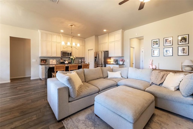 living area with baseboards, ceiling fan with notable chandelier, dark wood-style flooring, and recessed lighting