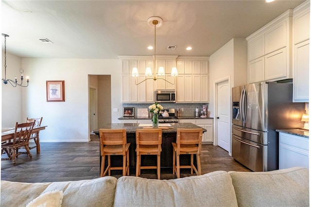 kitchen featuring a notable chandelier, stainless steel appliances, visible vents, backsplash, and a center island