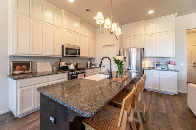 kitchen featuring appliances with stainless steel finishes, backsplash, a sink, and dark wood finished floors