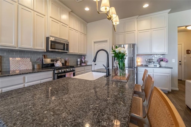 kitchen with appliances with stainless steel finishes, backsplash, a sink, and white cabinetry