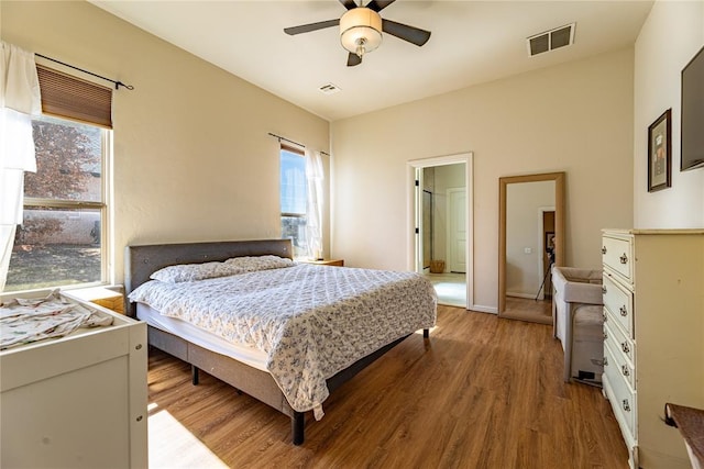 bedroom with baseboards, wood finished floors, visible vents, and a ceiling fan